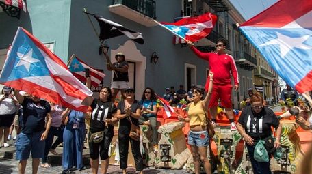 Demonstrators, some waving Puerto Rican national flags, gather