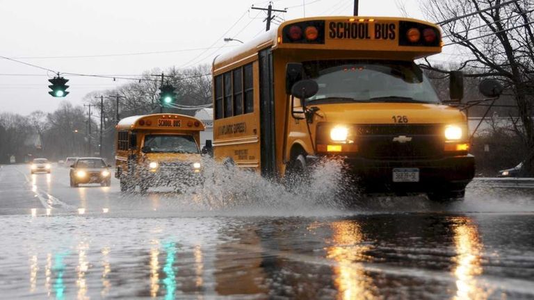 A school bus splashes through a large puddle