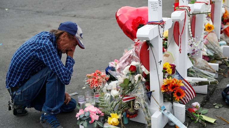 Antonio Basco cries beside a cross at a