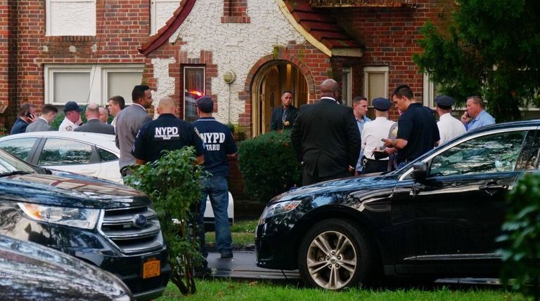 Police and others gather outside the Laurelton home