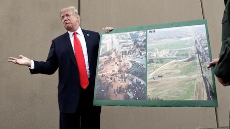 President Donald Trump holds a poster with photographs