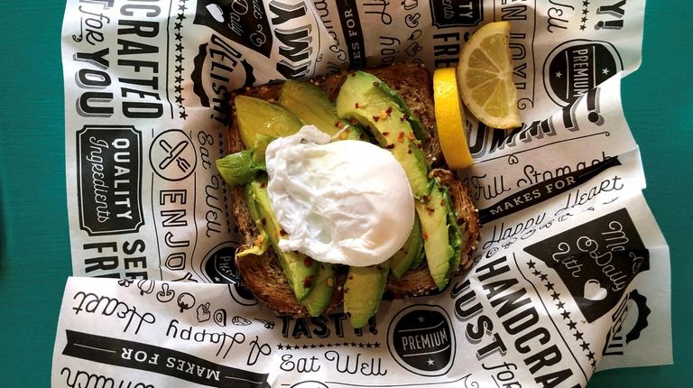 Avocado toast topped by a poached egg at