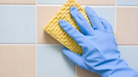 Cleaning the bathroom tiles with a scrubbing pad