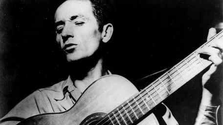 Woody Guthrie plays his guitar and sings in