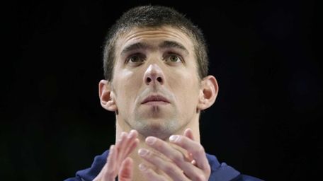 Michael Phelps claps during the medal ceremony for
