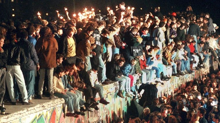 Young East Berliners celebrating atop the Berlin Wall