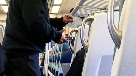 An LIRR conductor punches tickets on an eastbound