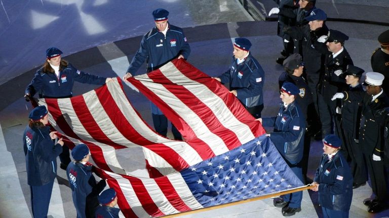 Olympians carry the tattered American flag from the