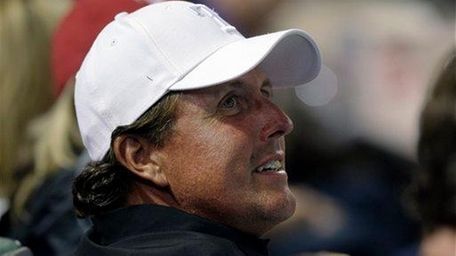 Phil Mickelson watches a baseball game between the