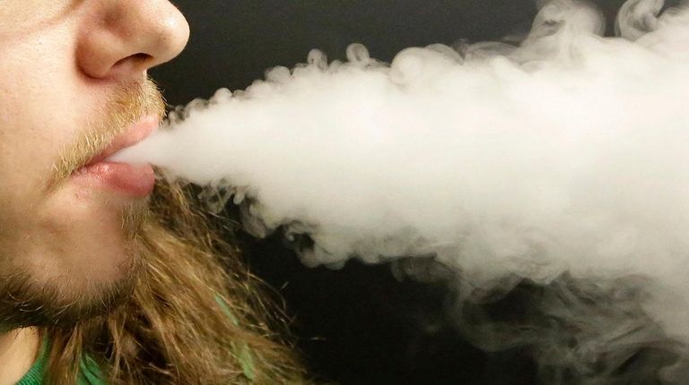 A man exhales vapor as he demonstrates the