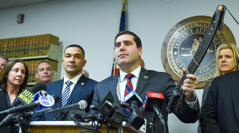 Suffolk County District Attorney Timothy Sini holds up
