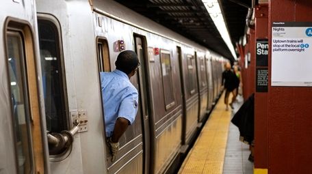 A subway train conductor checks the platform as