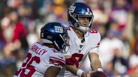 Daniel Jones #8 of the Giants hands the