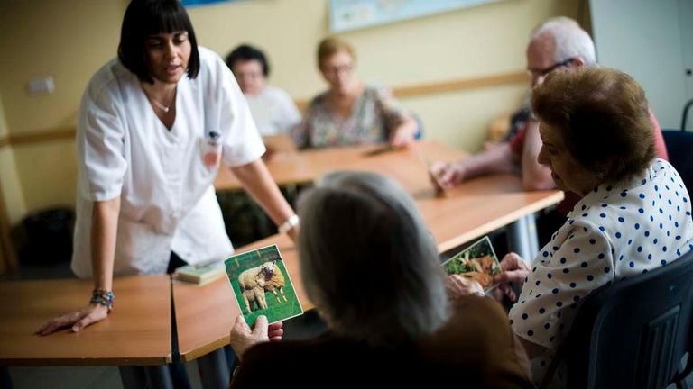 An elderly woman holds a picture of a