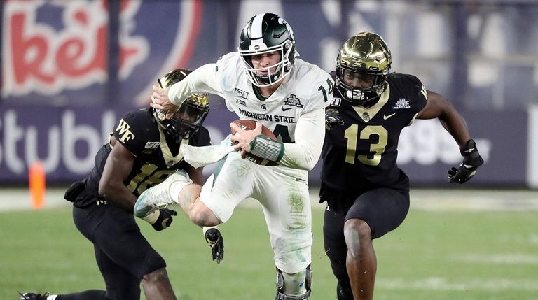 Michigan State quarterback Brian Lewerke tucks the ball