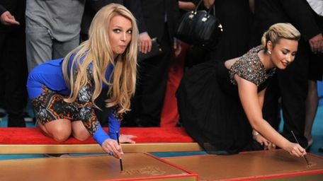 Judges Britney Spears, left, and Demi Lovato sign