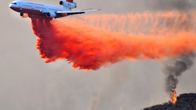 A DC-10 tanker drops fire retardant on a