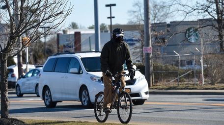 A man rides his bicycle along County Road