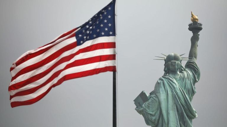 An America flag flies near the Statue of