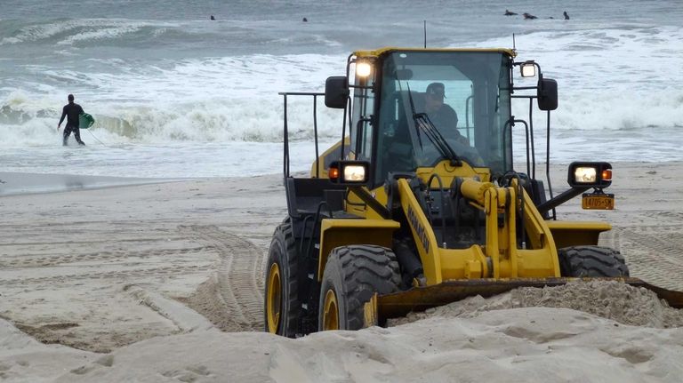 A bulldozer piles up sand on Long Beach