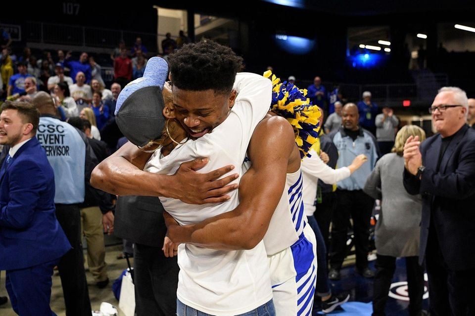 Hofstra guard Eli Pemberton, right, hugs a fan