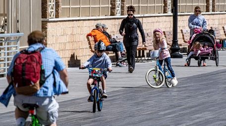 People walk and ride bikes along the boardwalk