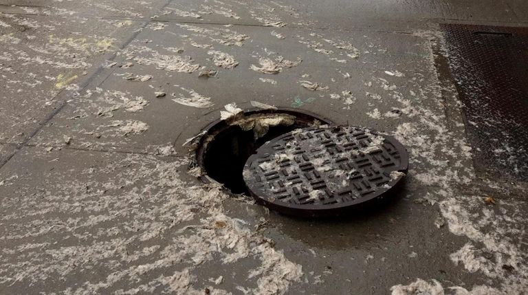 Wipes overflow out of a clogged manhole in