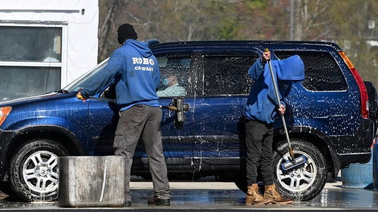 Workers from Robo Carwash clean a vehicle in