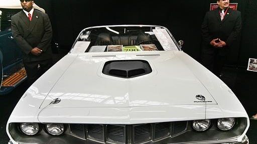 Security personnel stand near a rare 1971 Plymouth
