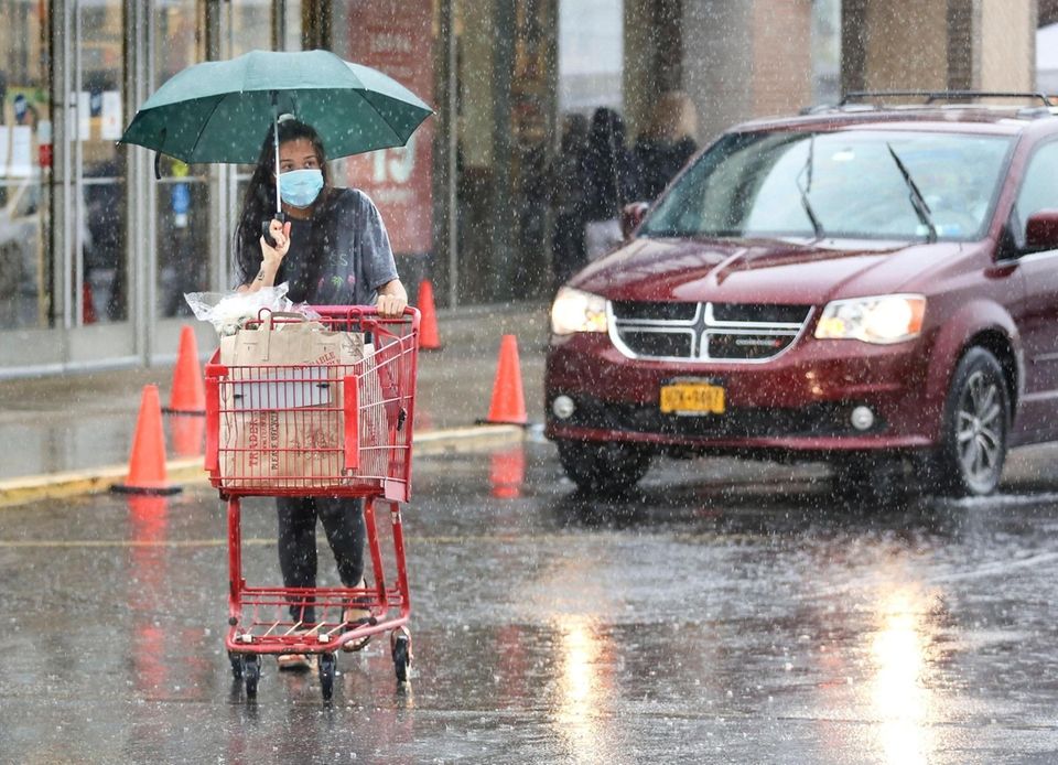 A shopper pushes her cart through the rain