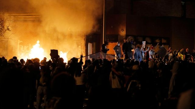 Protesters gather in front of the burning Minneapolis