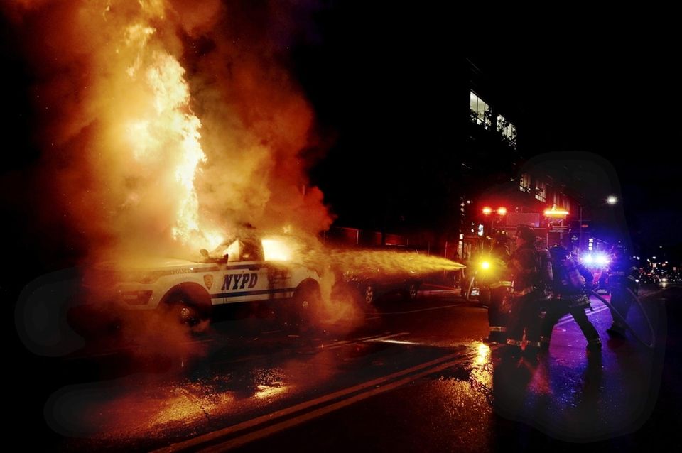 Firefighters work to extinguish a burning NYPD patrol
