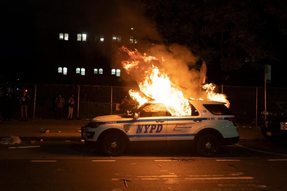 A NYPD vehicle is set ablaze as demonstrators