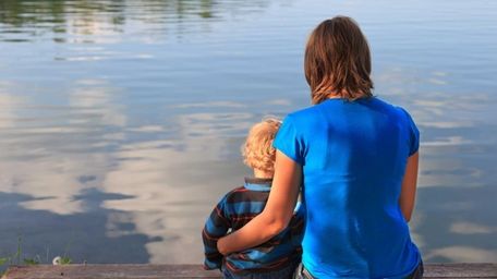 Mother and baby sitting on wooden dock.