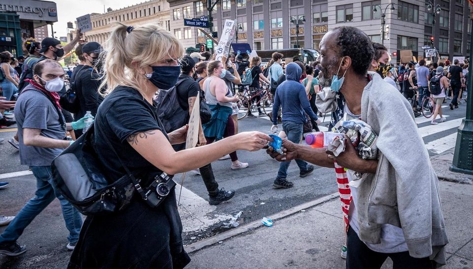 Protesters stop to give a homeless man money