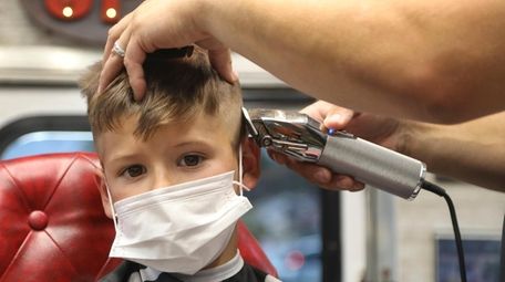 Jaxson Ronan, 6, gets his hair cut from