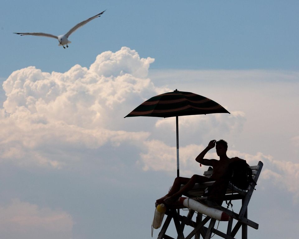 A lifeguard keeps watch over bathers as clouds