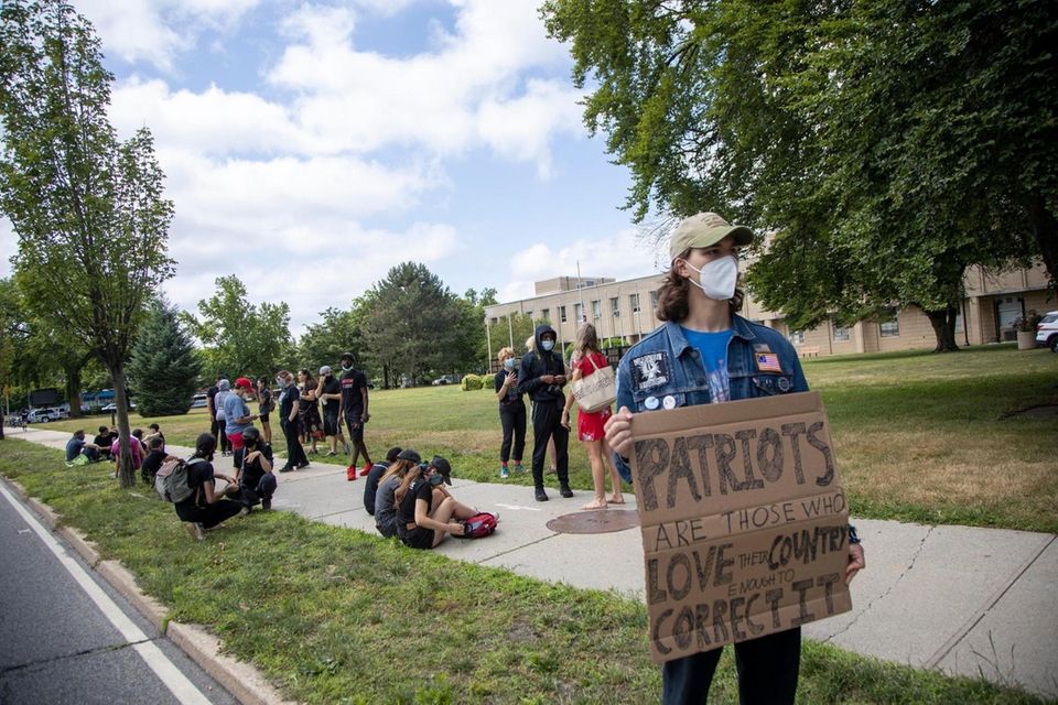Protestors wait outside Nassau Police headquarters for the
