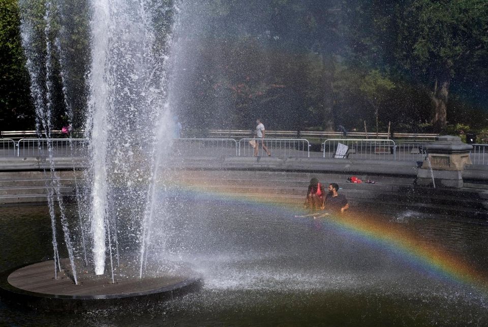 People stay cool as a rainbow forms in