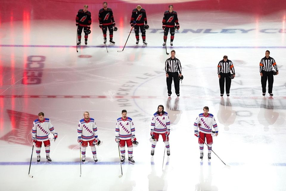 Members of the Rangers and the Hurricanes stand