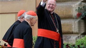 Cardinal Timothy Dolan waves to reporters as he