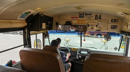 A school bus driver sits at the wheel