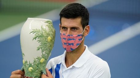 Novak Djokovic holds the trophy after defeating Milos