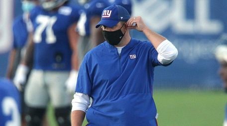 Giants head coach Joe Judge adjusts his mask