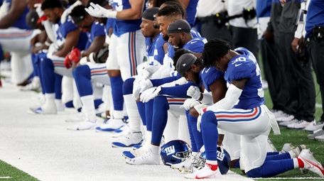 The Giants stand and kneel during the national