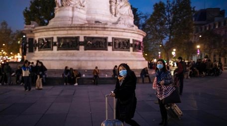 Tourists wearing protective masks walk on Republique square