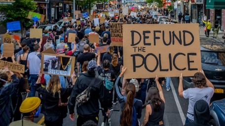 A participant holding a Defund The Police sign