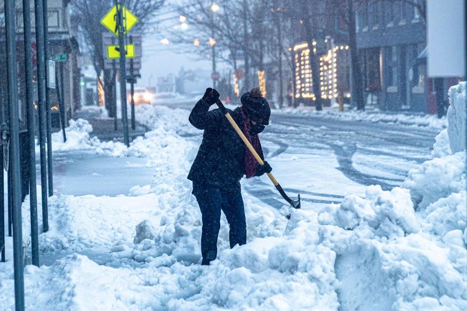 A woman shovels snow and ice on Main