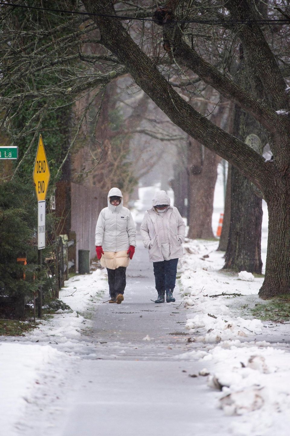 Two women walk down a sidewalk along Montauk