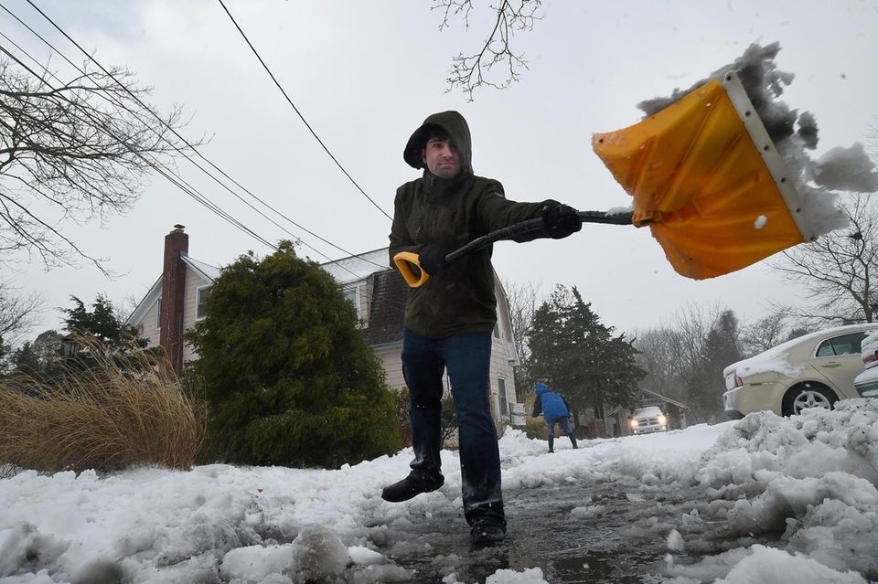 Joe Citlar shovels slushy snow from the sidewalk